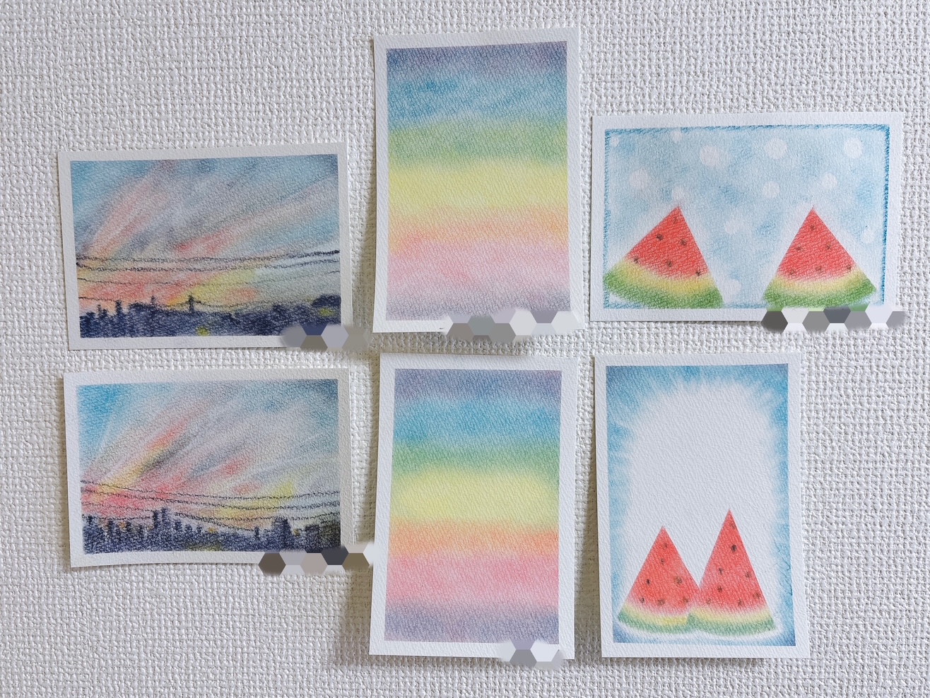 Six small Polaroid photos taped to a textured wall; left two show pastel sunset cityscapes and skies, cream borders around each image.