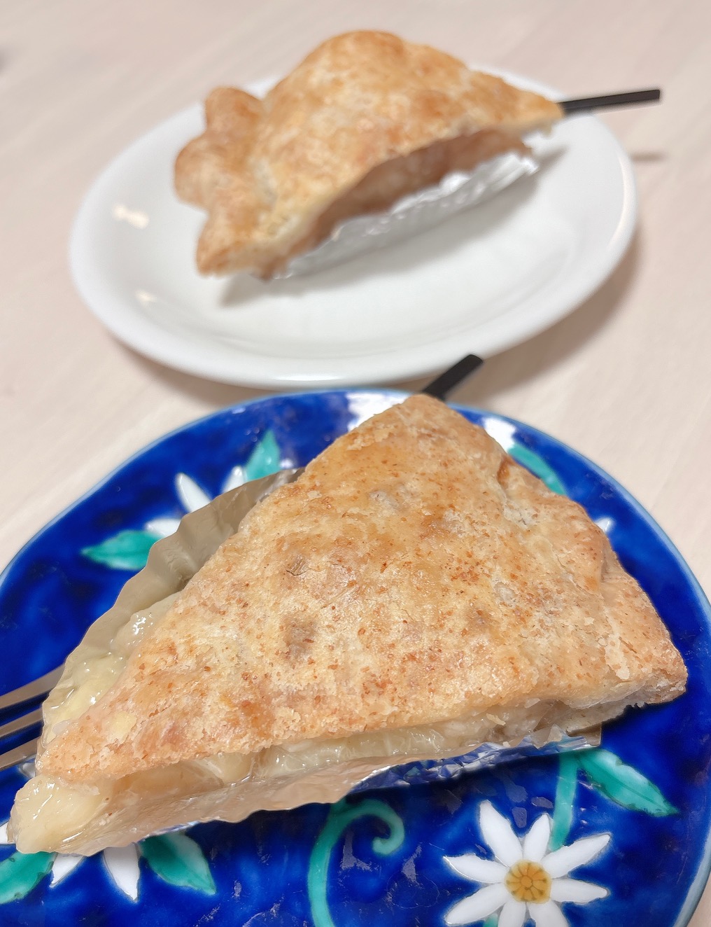Triangular slice of baked pie with a golden, flaky crust and creamy fruit filling on a blue plate