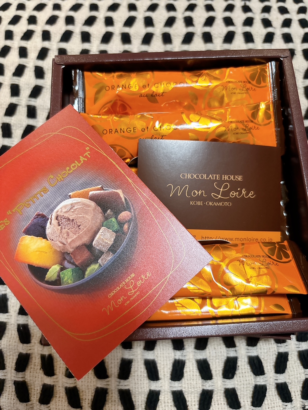 Box of orange-wrapped chocolates with a red Mon Loïre promo card in a brown gift box