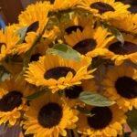 Bouquet of yellow sunflowers with dark brown centers and green leaves.