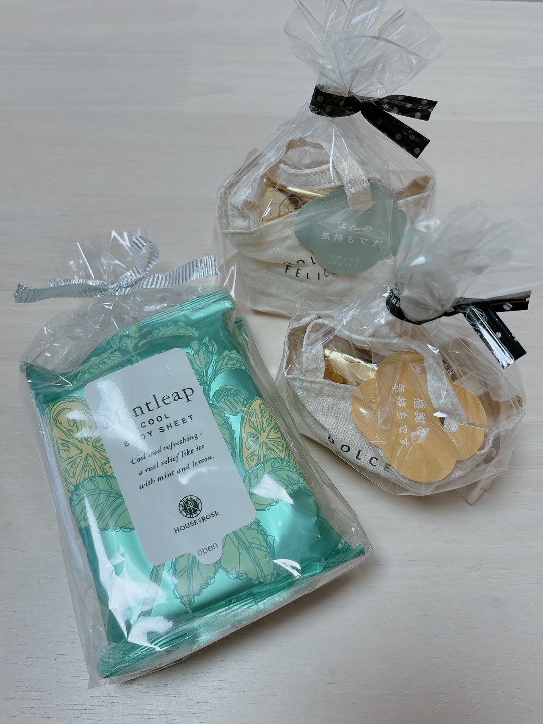 Two clear gift bags with black ribbons sit beside a turquoise Mintleap Cool Body Sheet package and a set of small wrapped items.