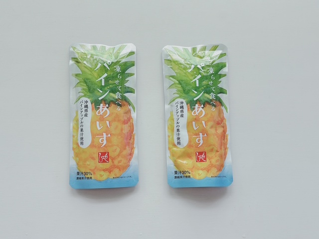 Two identical pineapple juice pouches with a pineapple illustration and blue gradient, placed on a light gray surface.