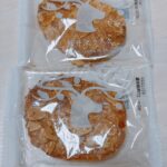 Two almond-topped rusks sealed in clear bags with white decorative designs and the label 'KARUIZAWA RUSK' visible on each package.