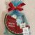 Blue cellophane gift bag tied with a red ribbon, containing a watermelon-themed kids' gift set with a penguin/toy figure and cookies.