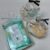 Two clear gift bags with black ribbons sit beside a turquoise Mintleap Cool Body Sheet package and a set of small wrapped items.