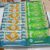 Display box with two stacks of Sugar Butter Sand cookies: blue wrappers on the left featuring a sandwich icon and a white tree, green wrappers on the right with a grape cluster and white trees.